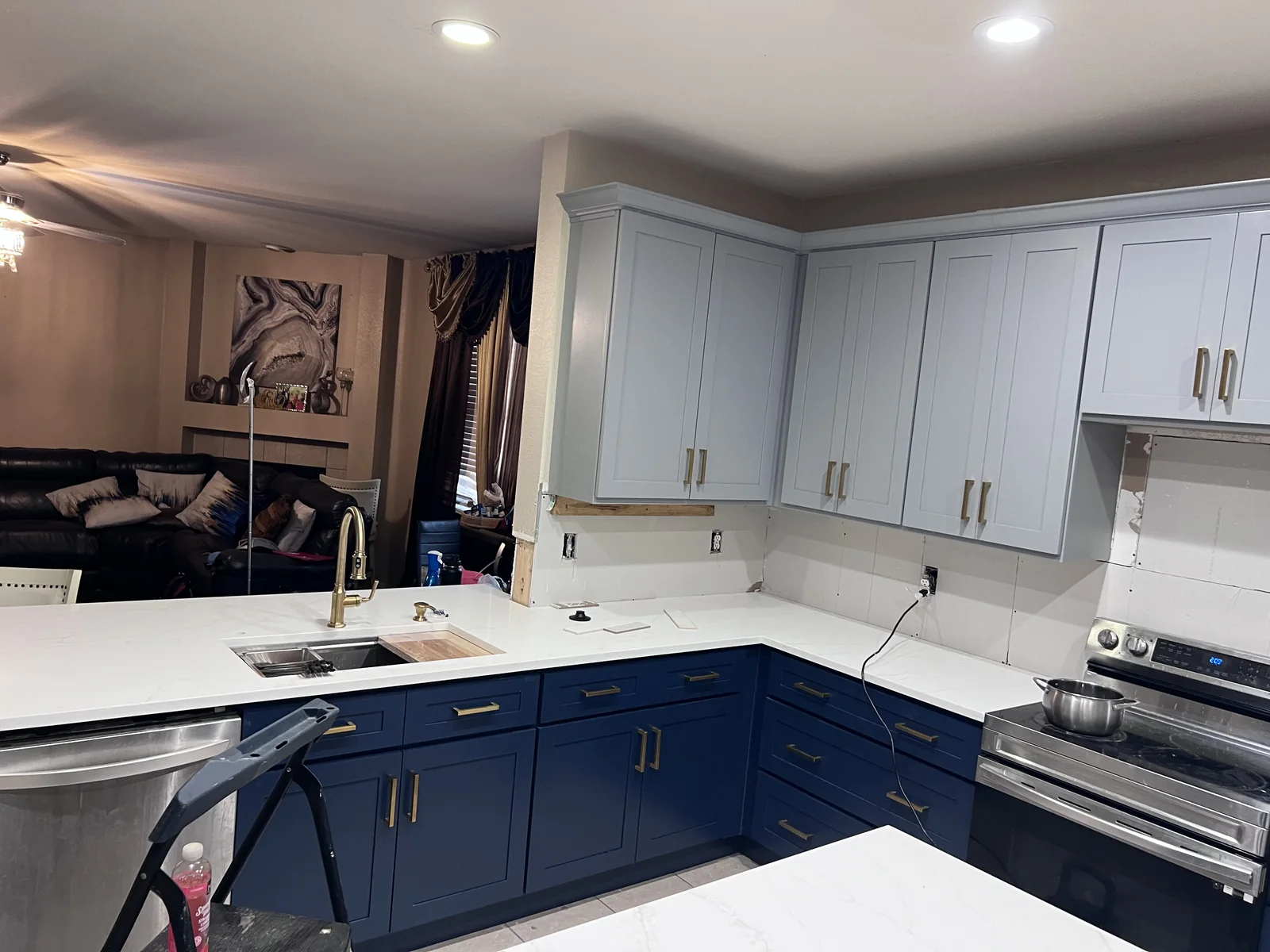 Blue-and-white corner kitchen with brass-toned handles and tiled backsplash